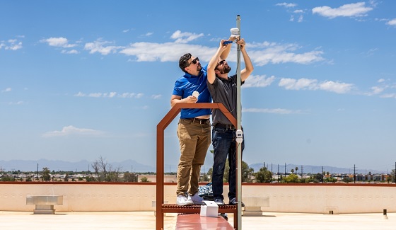 EnKoat co-founder Matthew Aguayo, assists Resource Innovations’ Peter Hamstra with the installation of a temperature and humidity tower outside the HDC facility. Photo courtesy of Matthew Aguayo.